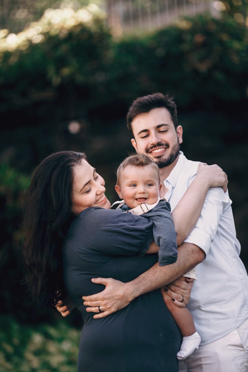Parents embracing their baby outdoors in warm evening light